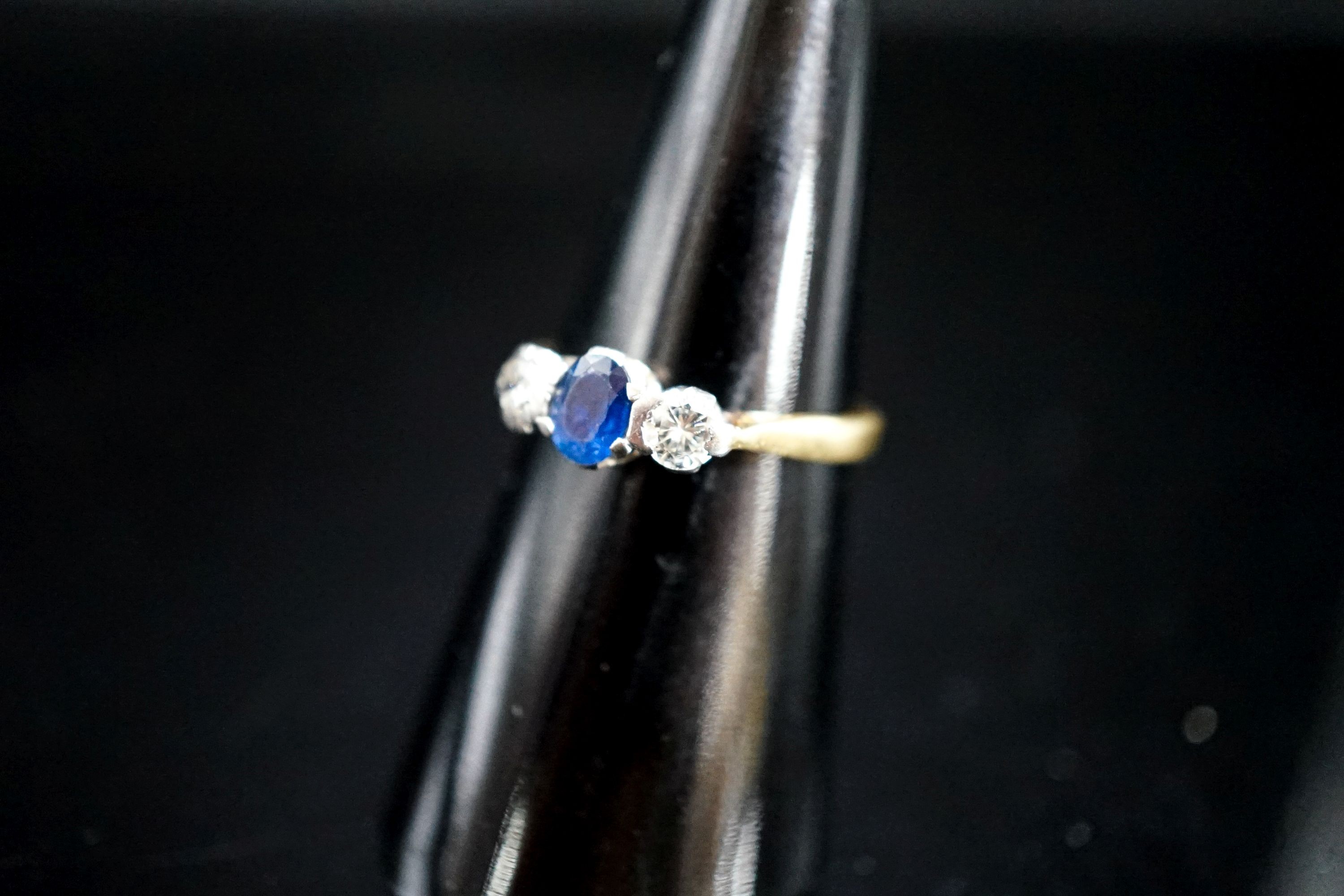 A modern 18ct gold, sapphire and diamond set three stone ring, size L/M, gross 3 grams.